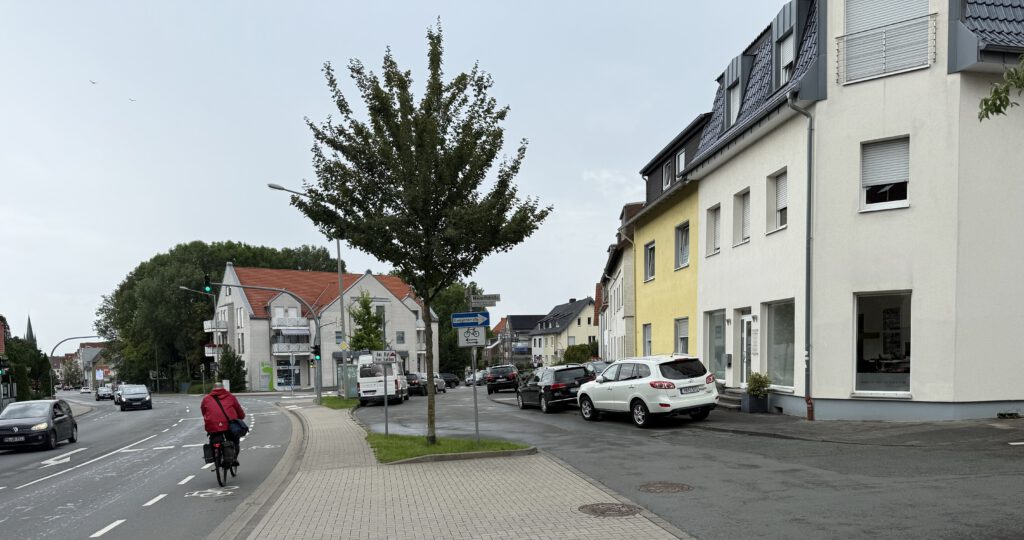 „Kreuzung an der Borchener Straße in Paderborn-Südstadt – versiegelter Platz mit wenig Begrünung, Blick auf Gebäude und Radweg“